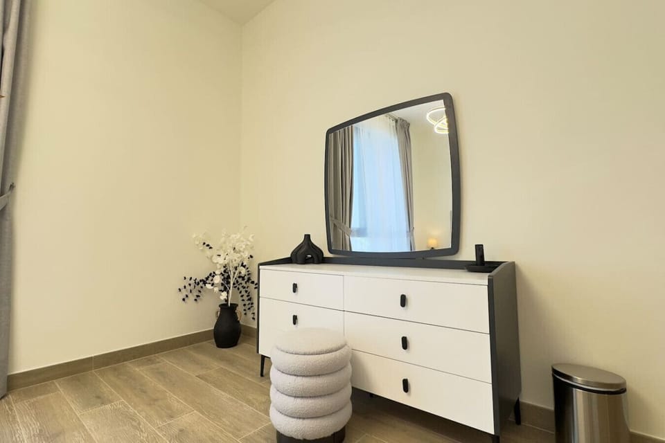 The bedroom`s storage solution includes a modern white dresser with clean lines and a large mirror, maximizing both function and style in the space.