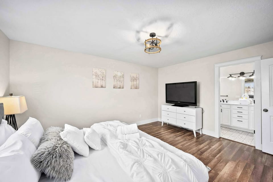 Drift off in your serene bedroom with crisp white linens, modern fixtures, and thoughtful touches like fluffy pillows and warm lighting.