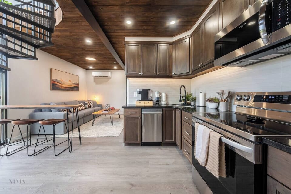 Modern open kitchen with stainless steel appliances flowing into the living and dining space.