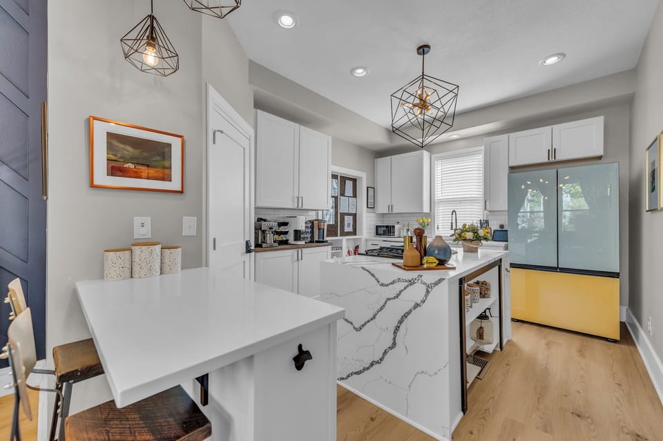 Chef’s kitchen with quartz counters, designer lighting & colorful fridge