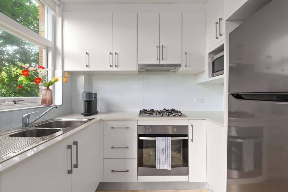 Prepare home-style meals with ease in a full kitchen featuring a gas cooktop, oven, microwave, fridge, and all the cooking essentials.