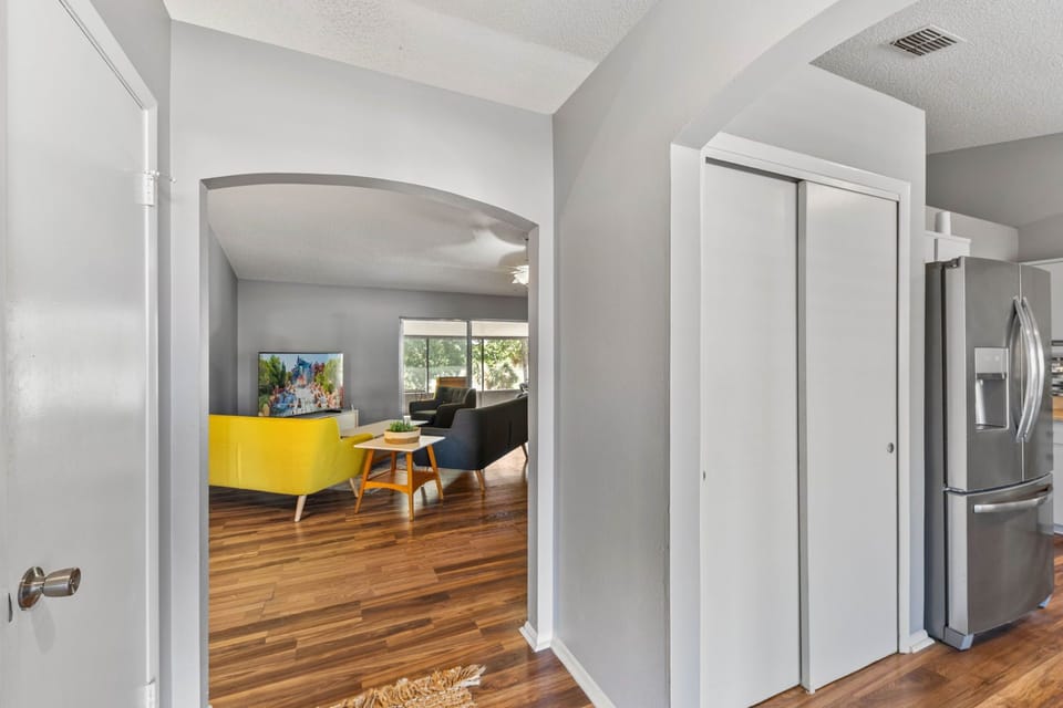Step into a welcoming entryway featuring two archways—one leading into the living room, where you’ll find stunning lake and garden views, and the other opening into the fully equipped kitchen, designed for both convenience and style.