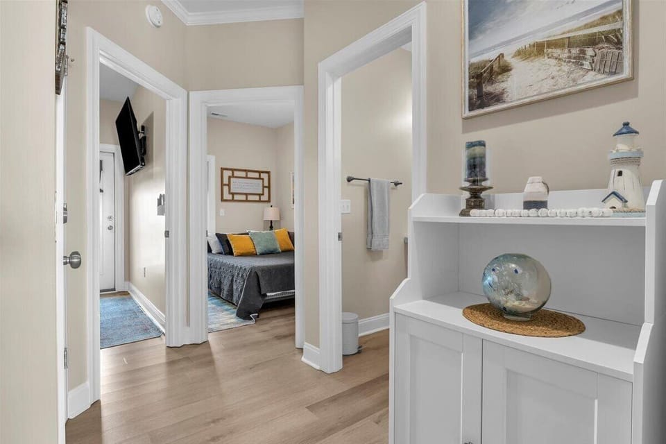 Step into your thoughtfully designed hallway, where coastal artwork and built-in shelving with curated décor create a welcoming atmosphere throughout your stay.