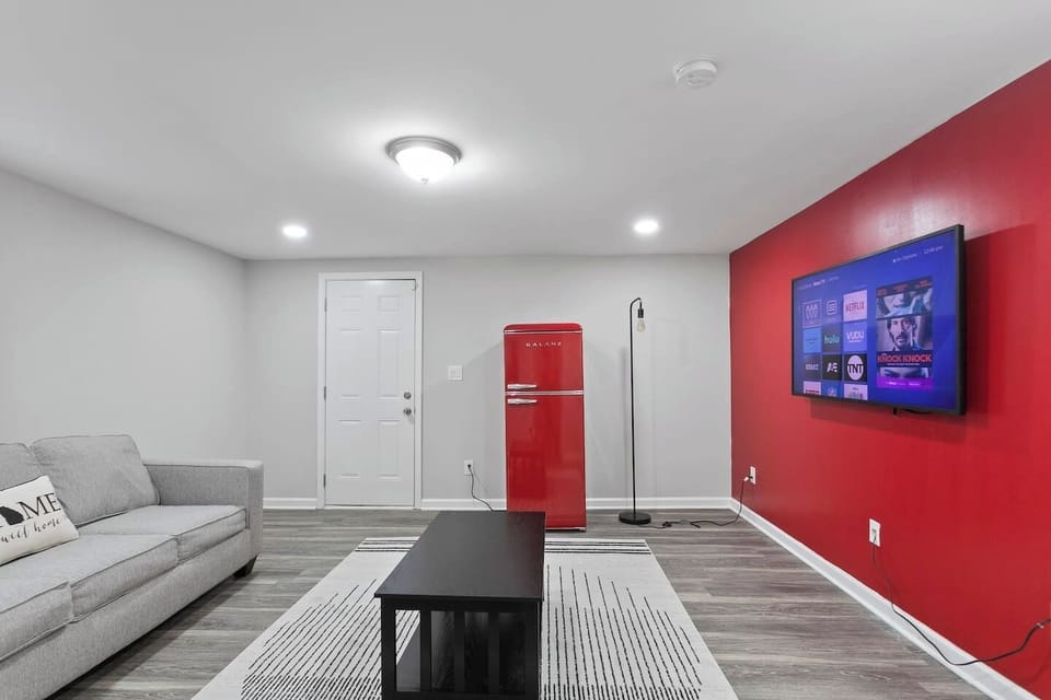 Your vibrant and cozy secondary living room, featuring a pop of boldness with a striking red accent wall and a retro red fridge. Unwind in this inviting space designed to add a touch of personality to your stay.