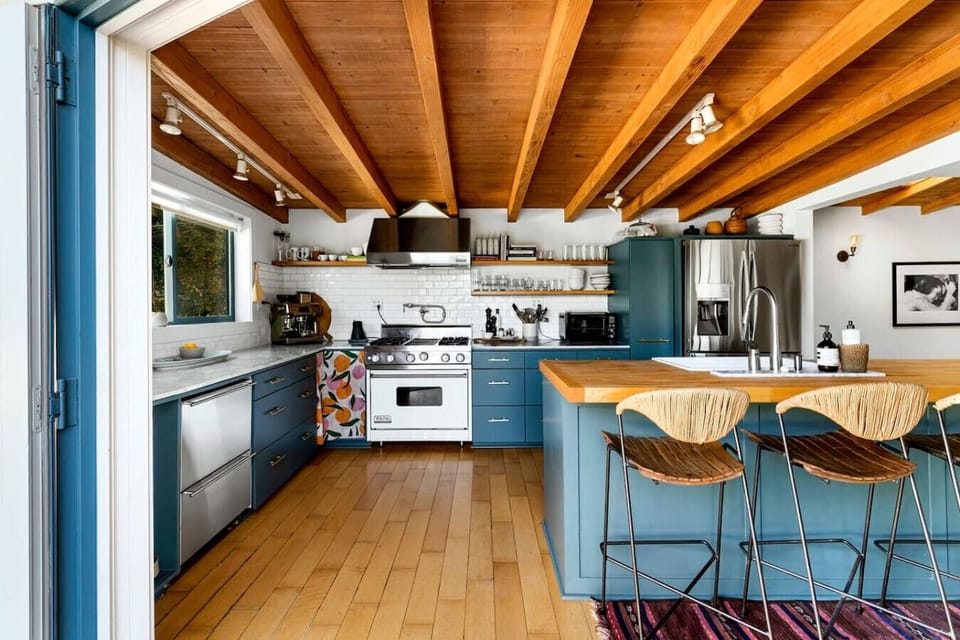 Stylish kitchen featuring a sleek center island, elegant wooden ceiling, and additional countertop seating—perfect for dining and entertaining.