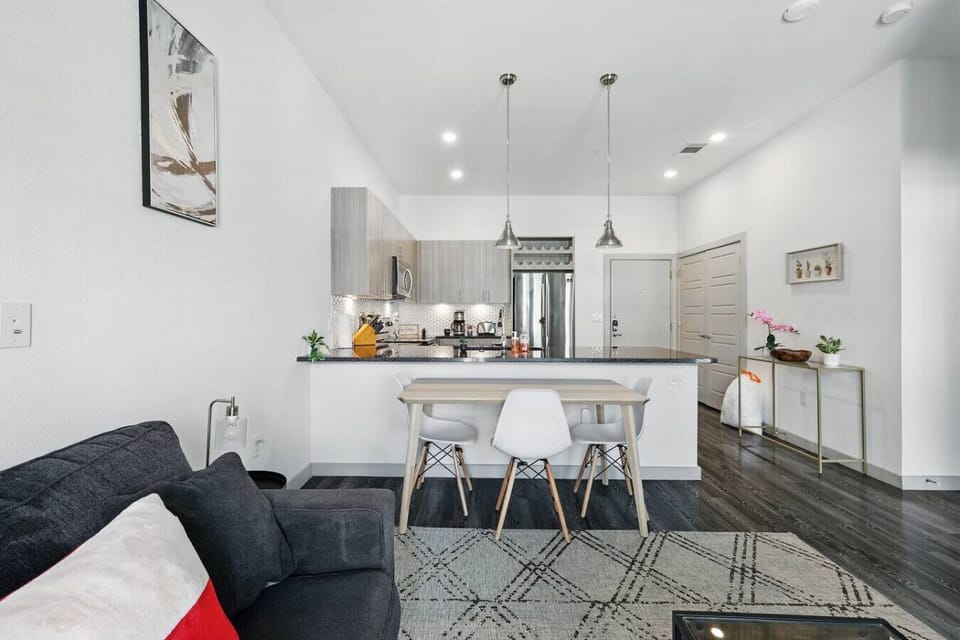 - Open plan dining area with island seating and cozy lounge - Sleek kitchen cabinets, stainless fridge and recessed lighting - Spacious apartment design with natural light and comfort