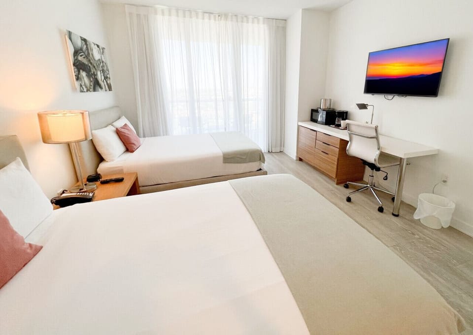 Spacious bedroom with a king-size bed, flat-screen TV, and bright natural lighting.