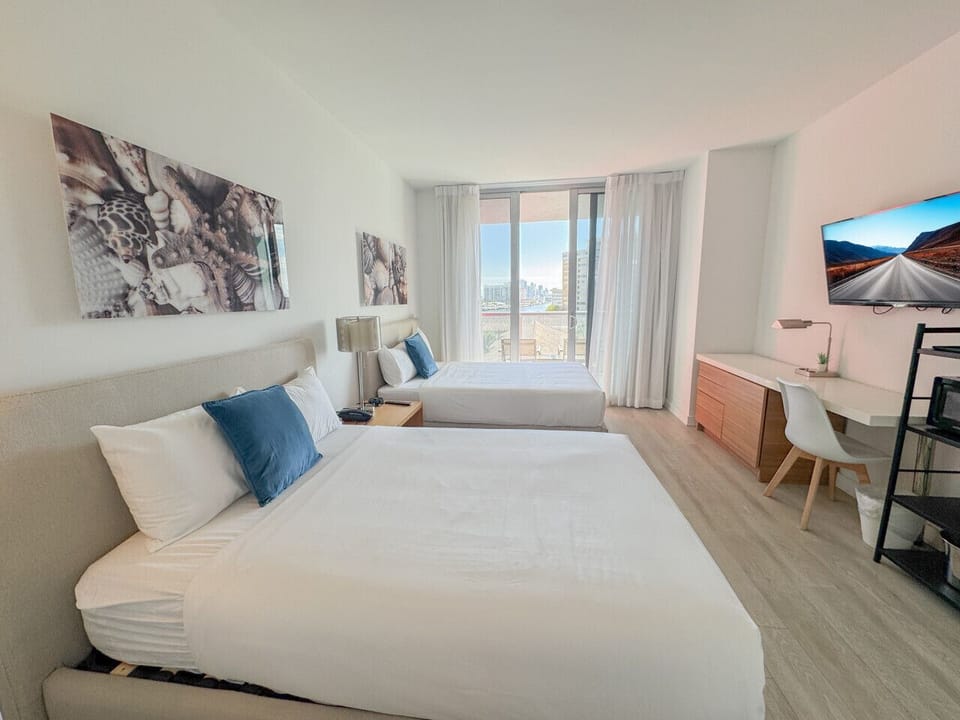 Bright room with two comfortable beds and outdoor views.