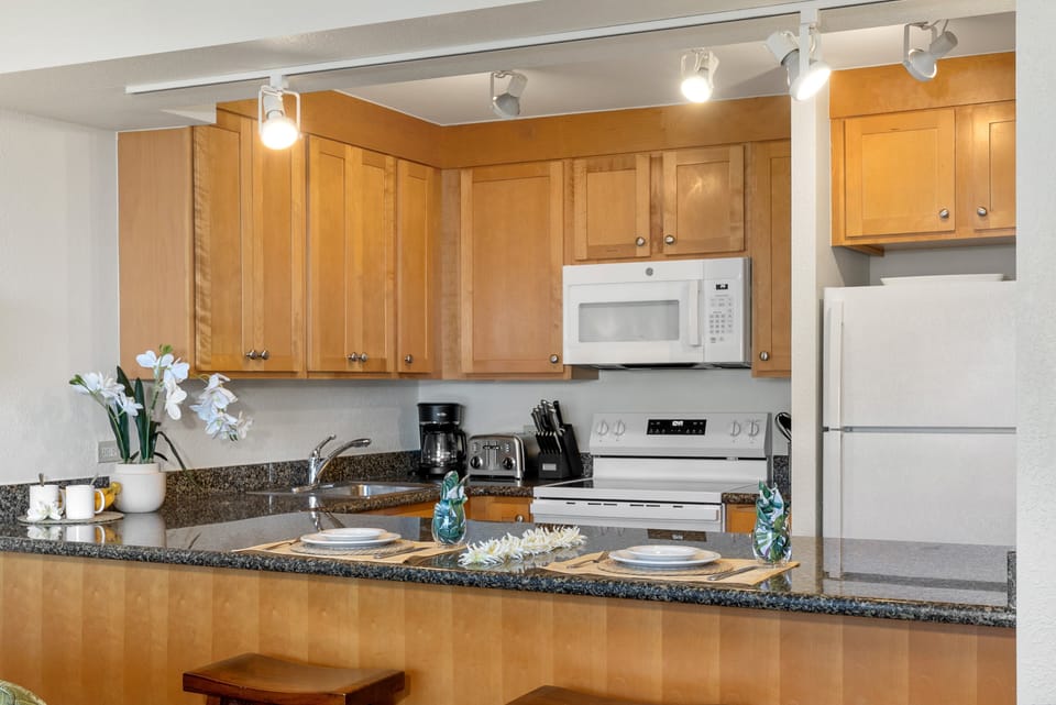 Spacious, fully stocked kitchen featuring wooden cabinetry, modern appliances, and ample counter space for preparing meals.