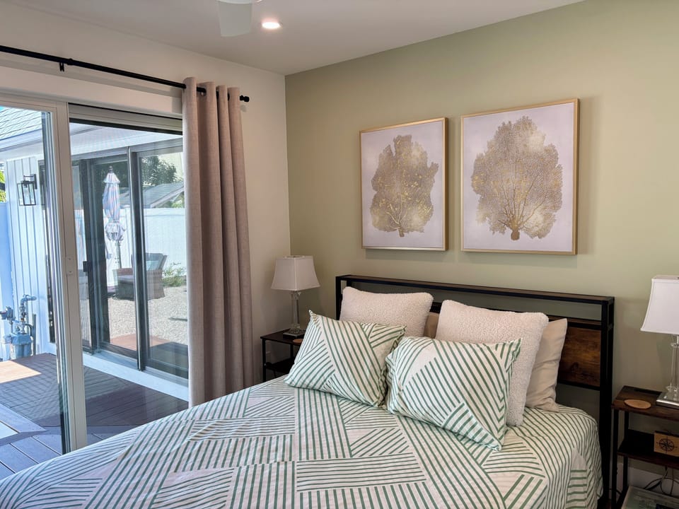 Primary bedroom: Queen bed, ceiling fan, blackout curtains, slider to backyard.
