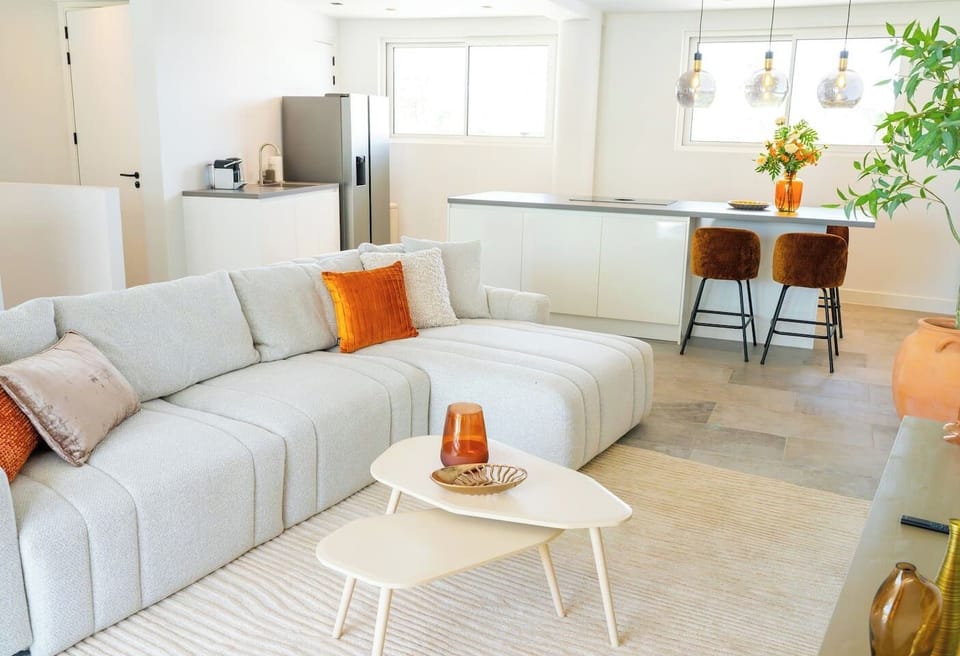 Open and airy space with a comfy sofa and a clean kitchen setup—great for relaxing, cooking, or just hanging out.