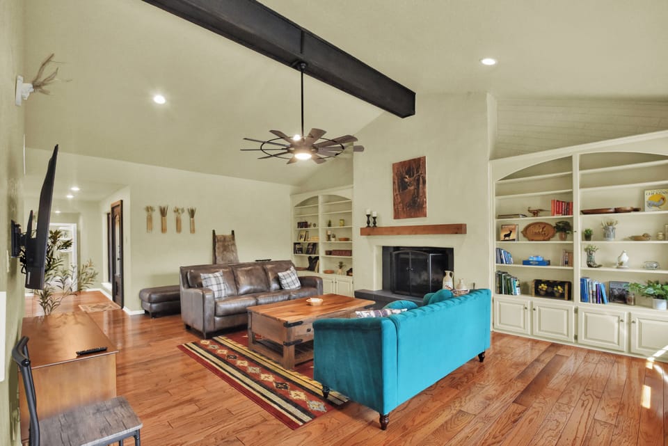 Open concept living room with 2 couches,  fireplace and large flat screen TV.  