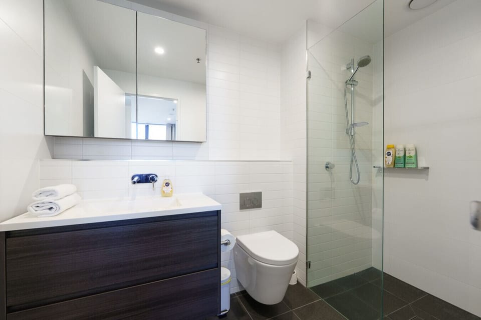 Modern bathroom with a clean shower and toilet, stocked with fresh towels and essential toiletries for your convenience.