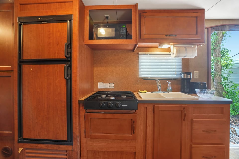 Full kitchenette with fridge, microwave, stove, and sink.








