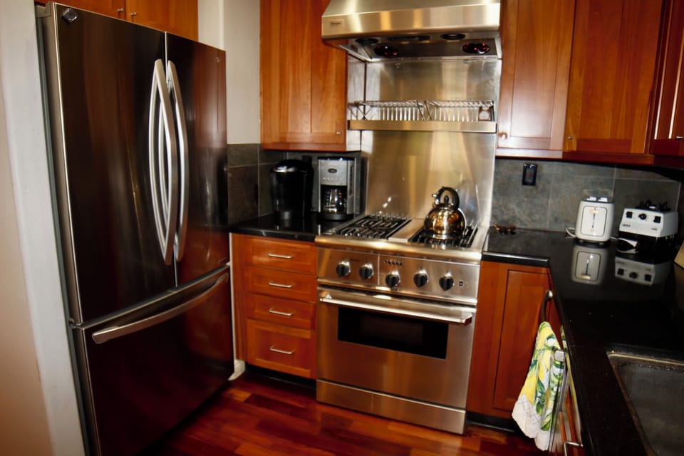Modern kitchen with stainless steel appliances, gas range,and rich wood cabinets