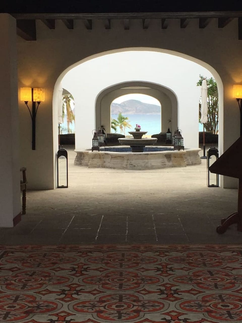 View from the lobby through the arched walkways, looking out towards the courtyard fountain and the sea.