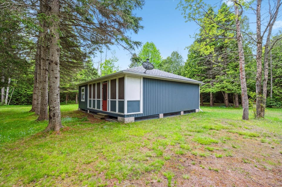 Encircled by mature pine and cedar, the cottage’s setting offers peaceful seclusion. The satellite dish atop hints at basic modern amenities, but the mood is all about unplugging and breathing in the stillness.