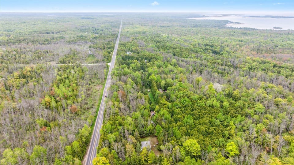 This aerial corridor shot puts Chief’s Cottage in context — one of just a few homes tucked into a stretch of green, with a long winding road threading through the forest. The approach alone sets the tone for an unplugged, restorative stay.
