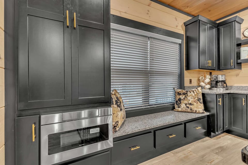 Kitchen window bench with built-in drawers, sleek black cabinetry, and microwave nook—perfect for morning coffee or extra seating.