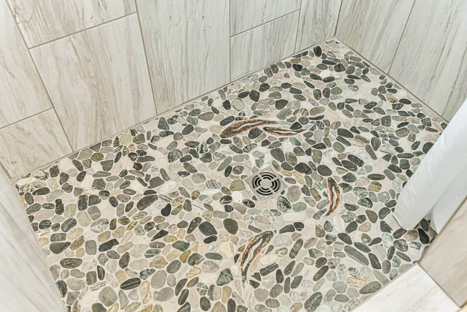 Our unique tile shower features a natural pebble floor. Watch out for the fish!