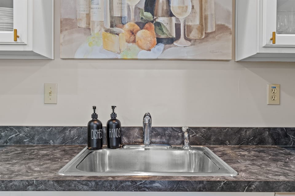 Fully stocked kitchen with white appliances, stainless sink, dishwasher, microwave, toaster, and coffee maker.