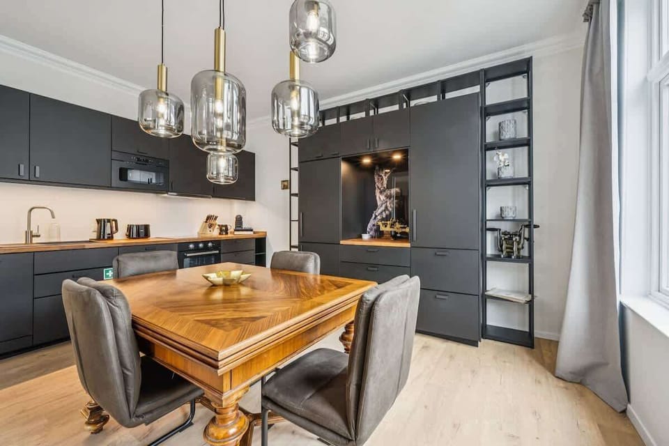 Moderne Küche mit stilvollem Essbereich, hochwertigen Geräten und viel Platz. Warme Holzelemente treffen auf elegantes Design – ideal zum Kochen, Essen und Zusammensitzen.