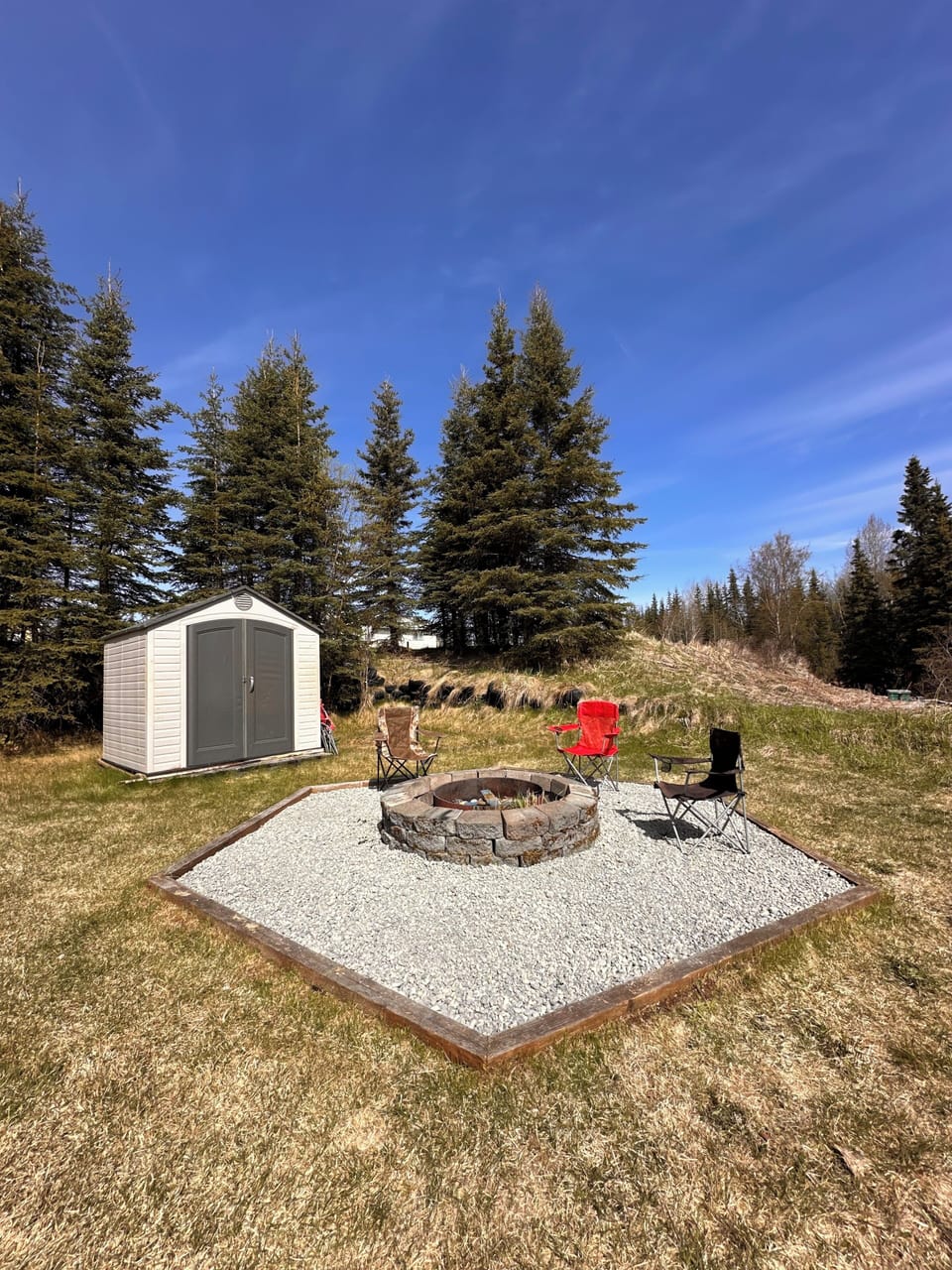 The fire pit for our guests, equipped with firewood and cornhole in the shed.
