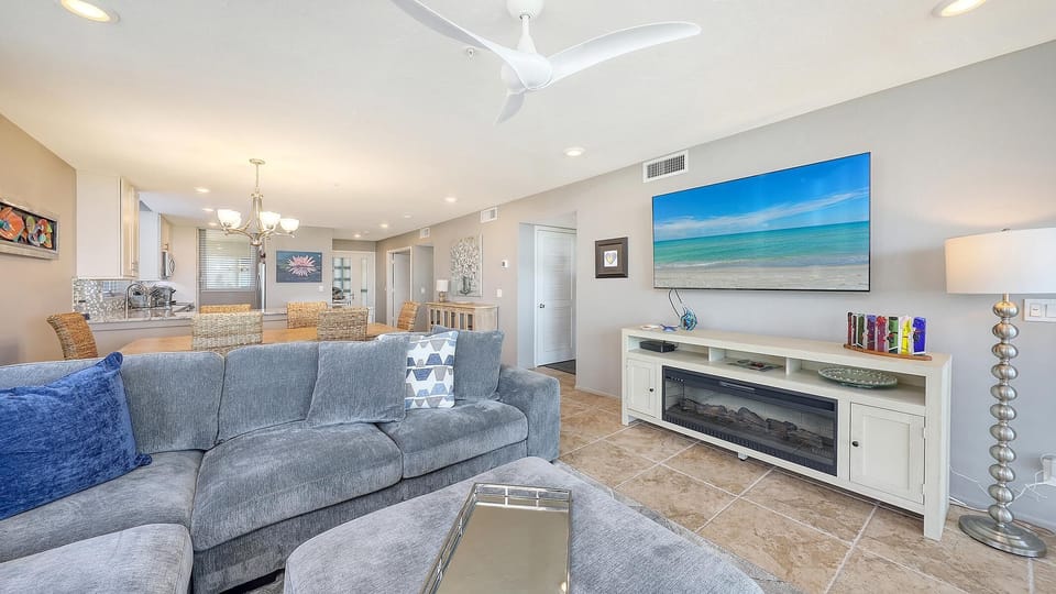 Flat-screen TV above white media console with electric fireplace and decorative glass sculpture.