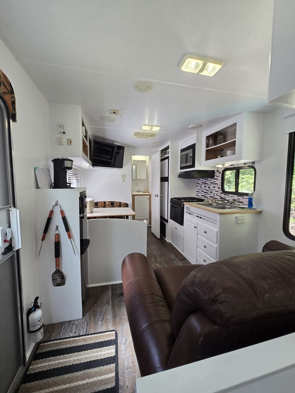 Cozy Cove Trailer - view from the bedroom. Kitchen with light house keeping items.Coffee/tea station, salt & pepper. As well as dishes, pots, pans, mugs, glasses etc. Drinking water is supplied (hot/cold) via cooler.
