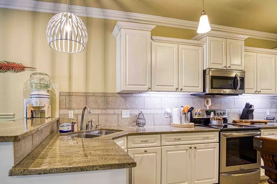A second kitchen angle shows the granite breakfast bar, double sink, range, microwave, and cabinet storage.