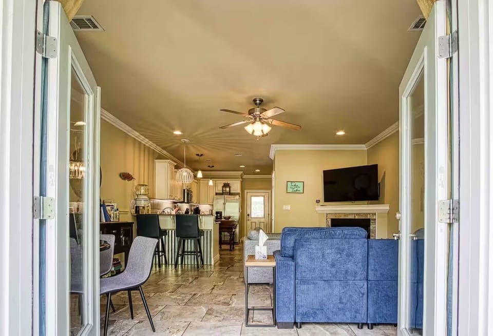A view through the waterside doors reveals the connected living room, fireplace, kitchen, and breakfast bar.