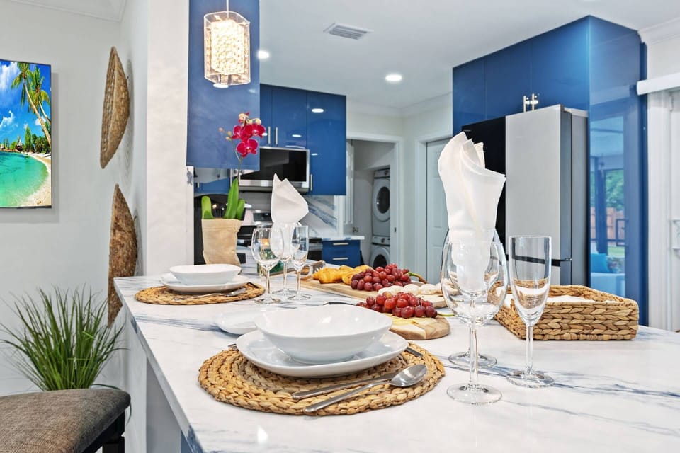 Modern marble kitchen island w/ stylish place settings and direct views of the pool combining indoor comfort with Fort Lauderdale’s outdoor lifestyle