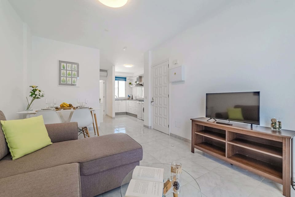 Open-Concept Living Area with a Dining Table, Sofa-Bed, Smart TV, AC & Plenty of Natural Light. 