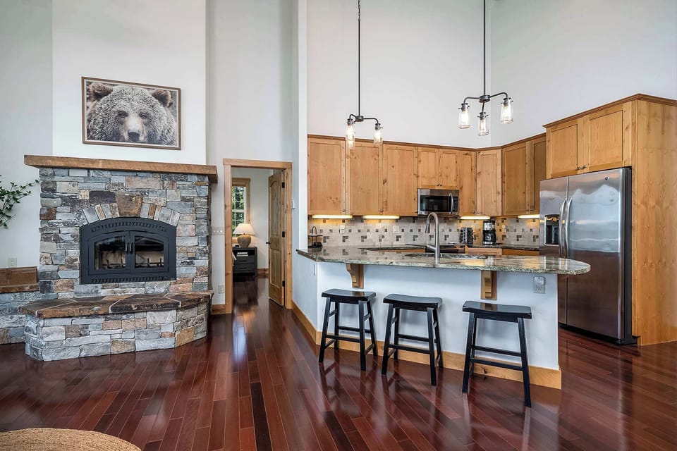 Main level indoor fireplace and kitchen with breakfast bar seating.
