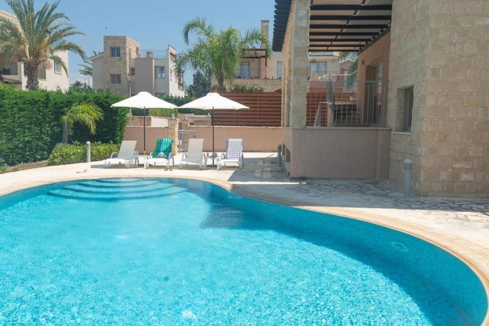 Private kidney shaped pool with sun loungers and parasols