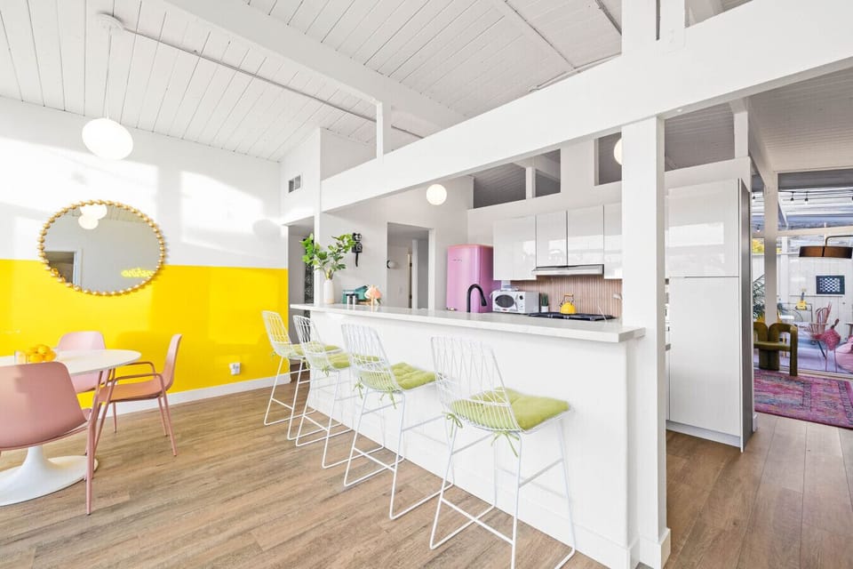 A cheerful kitchen and dining space bursting with color, light, and retro flair.