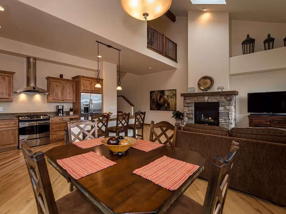 - Enjoy hearty meals and game nights in this warm, open space with wood beam accents
- Stone fireplace adds a cozy touch while vaulted ceilings make it feel grand
- Cooking, dining, and lounging all come together seamlessly here