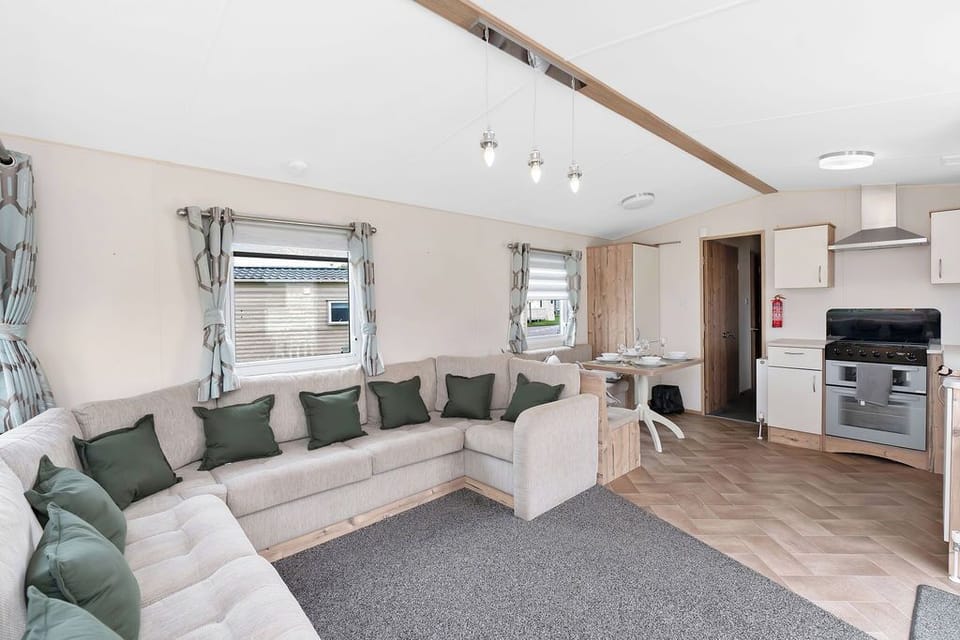 Spacious and modern living area with a large corner sofa, stylish decor, and a well-equipped kitchen—perfect for relaxing and socializing.