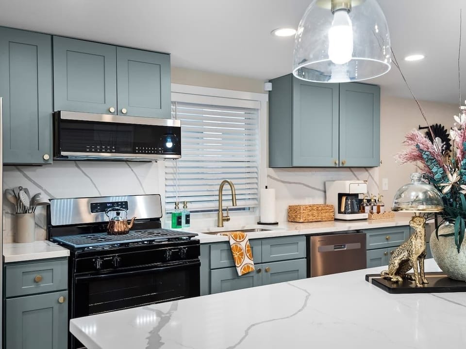 Modern kitchen details w/ sleek countertops, gold accents & window above the sink.
