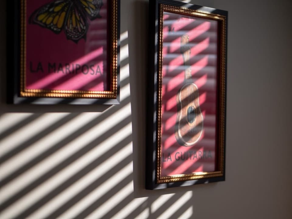 Close-up wall art detail w/ warm sunlight casting striped shadows.