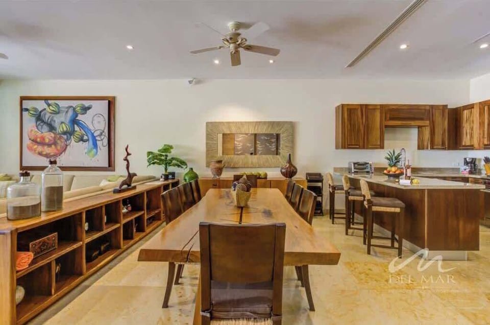 Spacious dining room w/ wood shelving, round table & open layout flowing into the kitchen.