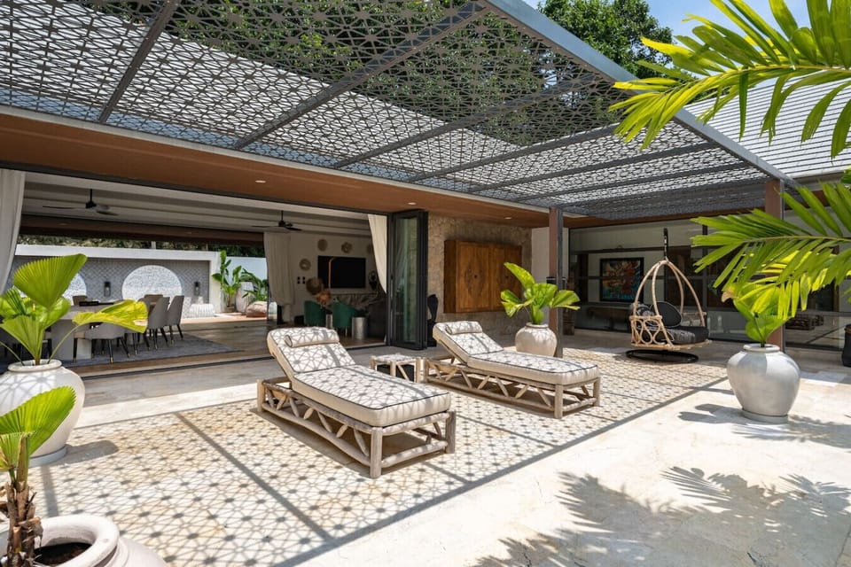 Shaded outdoor lounge with elegant daybeds and lush tropical garden surroundings