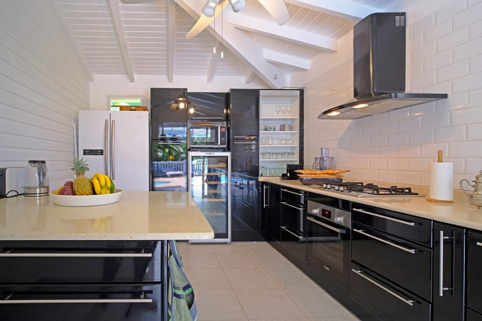 The kitchen and its island of the villa Les Arbres Voyageurs is fully equipped with a large refrigerator and a wine cellar, ideal to receive family and friends and enjoy a wonderful holiday in Guadeloupe