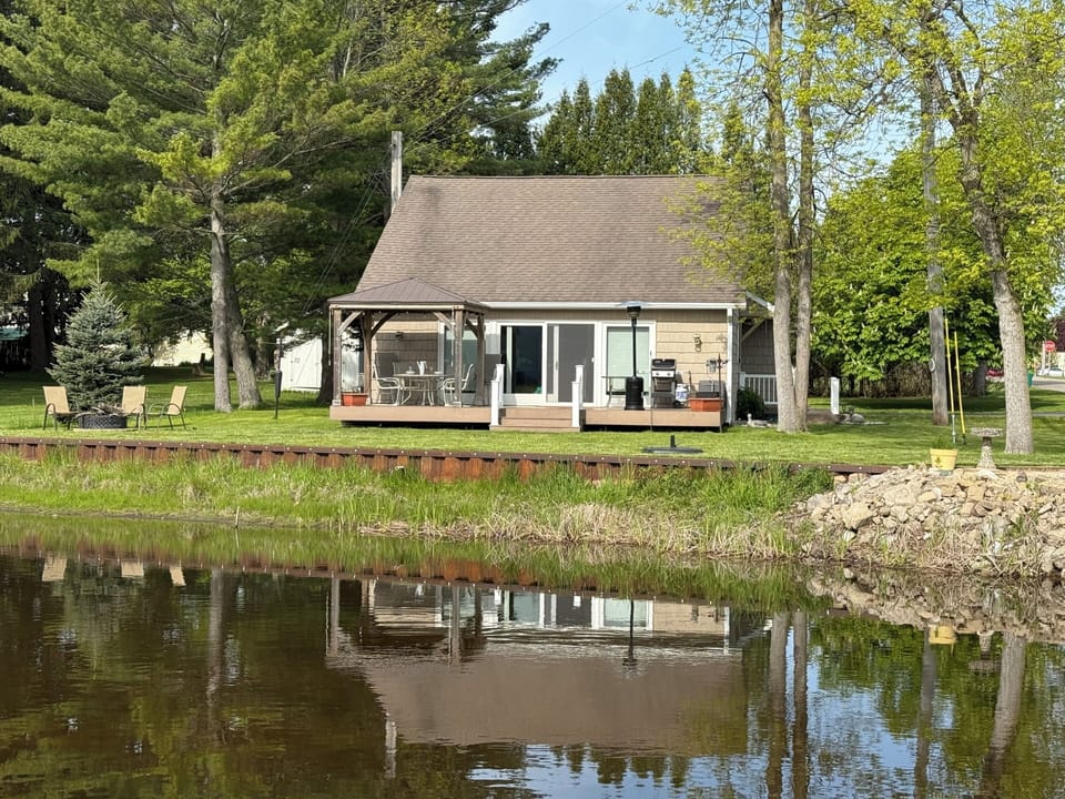 View of cottage from across the river. Riverside firepit on left. 