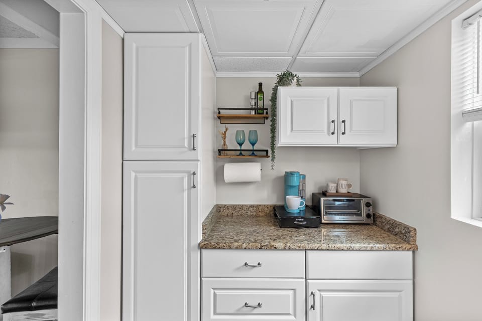 Prepare simple meals in the well‑equipped kitchenette featuring a cooktop, microwave, small fridge, and a Keurig + Carafe Coffee Maker.