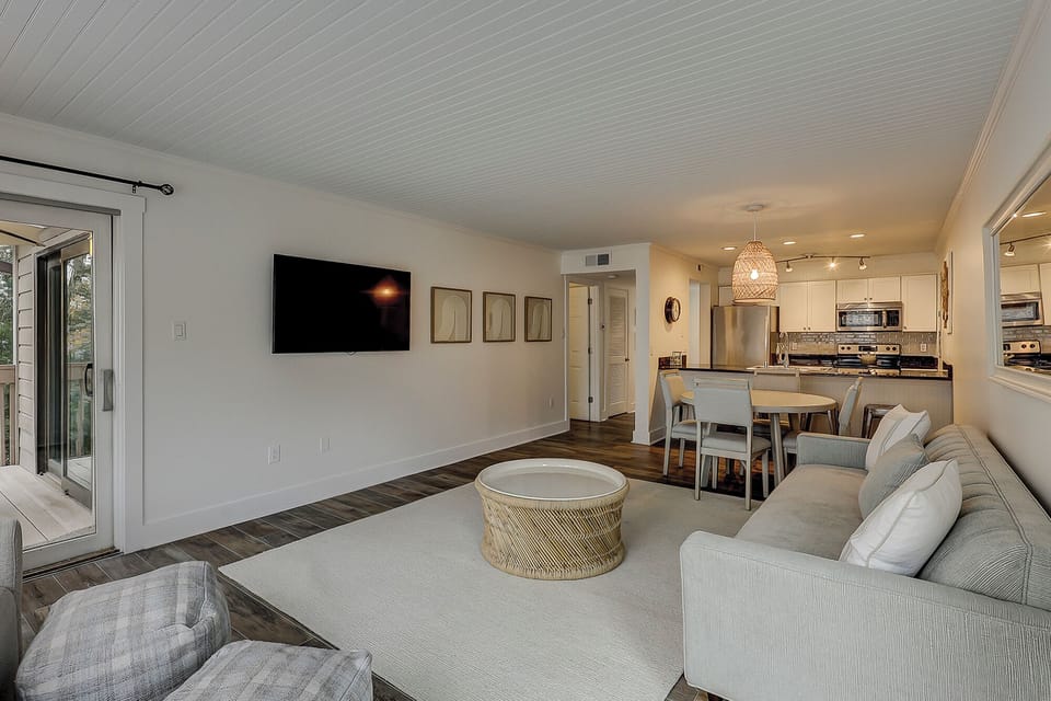 Living area with flatscreen tv, comfortable couches, and a dining table featuring 4 chairs.
