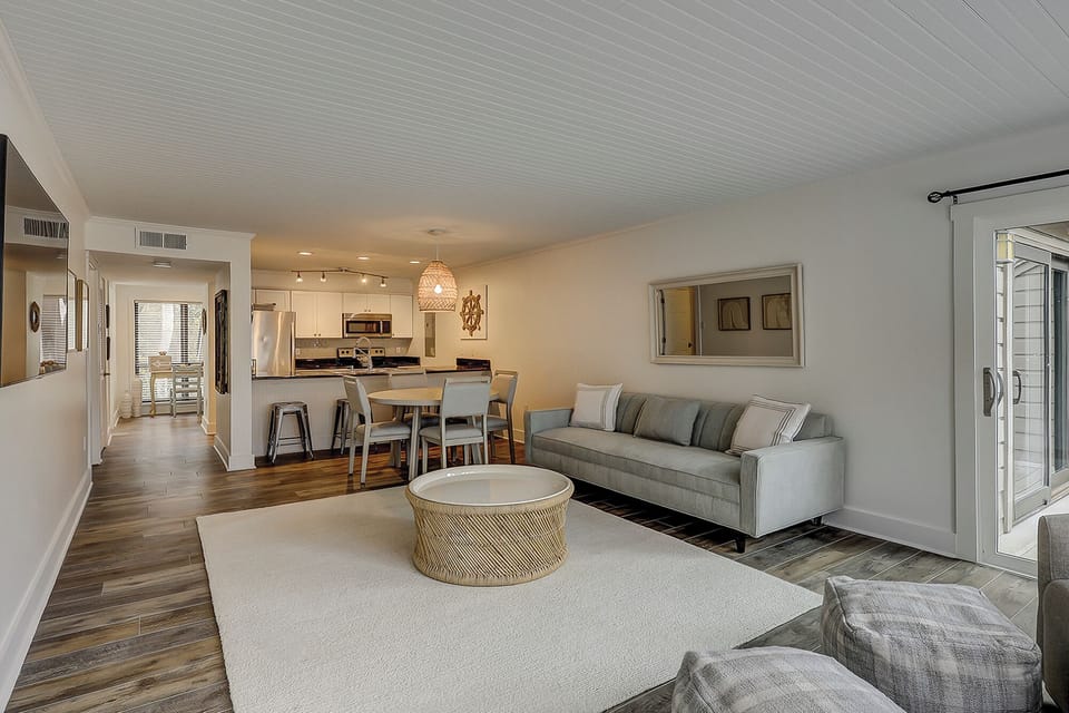 Living area with flatscreen tv, comfortable couches, and a dining table featuring 4 chairs.