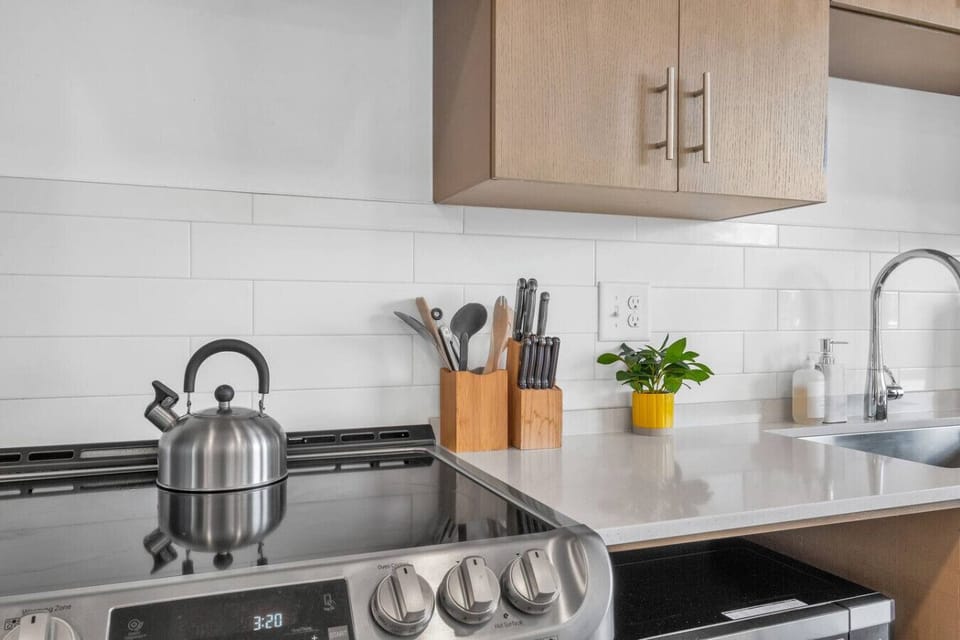 - Stainless steel stove with kettle and knife block set   - Modern sink area with sleek fixtures and bright workspace   - Open kitchen design perfect for home cooking
