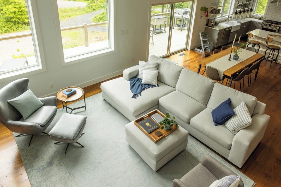 Cozy reading corner with large windows framing the lush surrounding landscape.