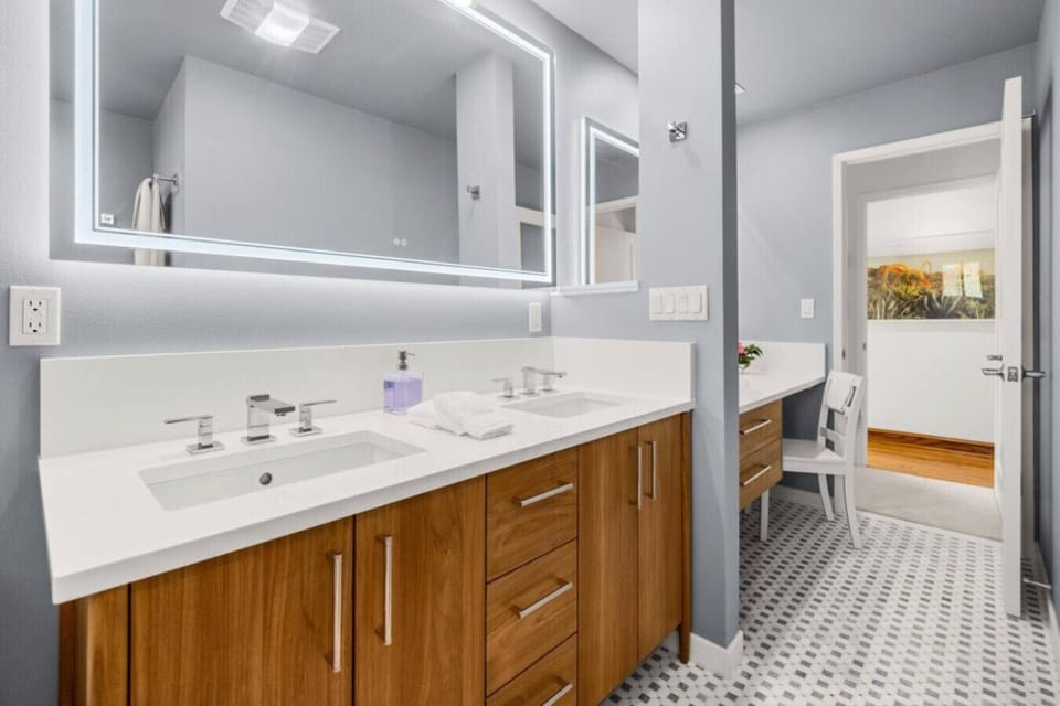 Both bathrooms feature solid teak cabinetry with polished chrome fixtures and white quartz countertops and backsplashes.